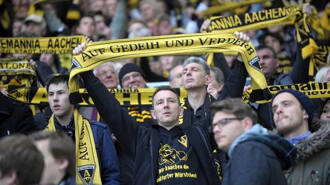 Ein Aachener Fan hält einen Schal mit der Aufschrift "Auf Gedeih und Verderb" hoch.