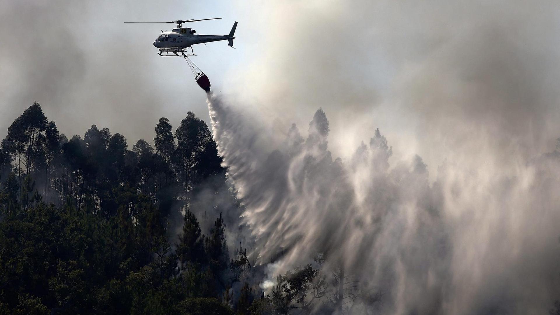 Ein Helikopter entlädt Wasser über einem Waldbrand in Serra Monchique. Ein Helikopter entlädt Wasser über einem Waldbrand in Serra Monchique.