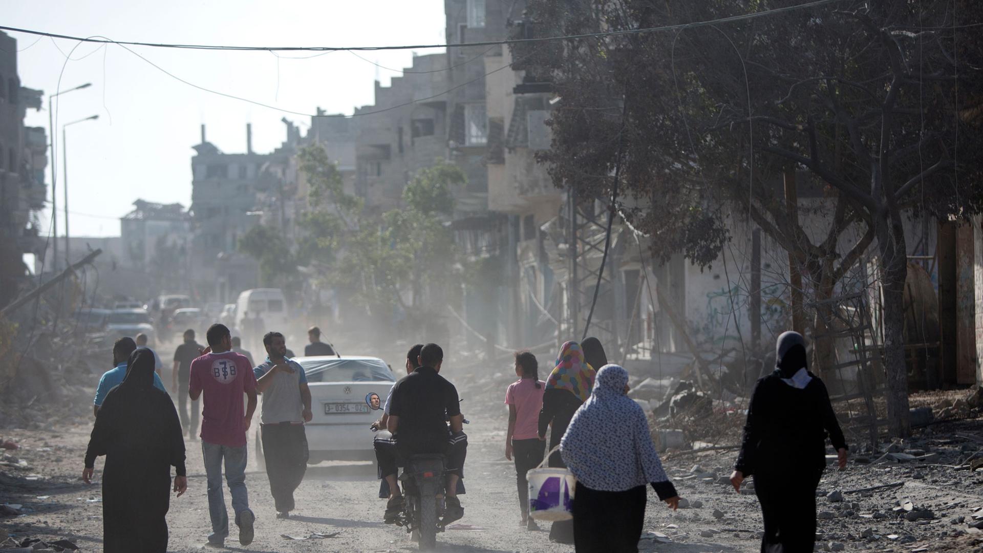Eine Gruppe von Palästinensern läuft durch eine staubige Straße, um zu ihren Wohnungen zurückzukehren, die sie wegen der Kämpfe zwischen israelischer Armee und Hamas verlassen haben. Eine Gruppe von Palästinensern läuft durch eine staubige Straße, um zu ihren Wohnungen zurückzukehren, die sie wegen der Kämpfe zwischen israelischer Armee und Hamas verlassen haben.