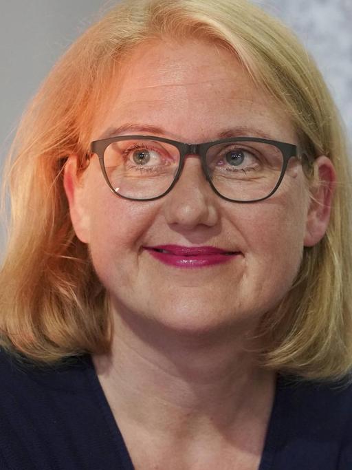 Lisa Paus sitzt auf einer Bühne und schaut freundlich ins nicht sichtbare Publikum.