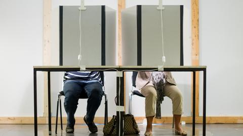 Ein Mann und eine Frau sitzen am 27.08.2013 in einem Wahlraum im Neuen Rathaus in Hannover (Niedersachsen) und füllen ihre Stimmzettel für die Bundestagswahl 2013 aus.