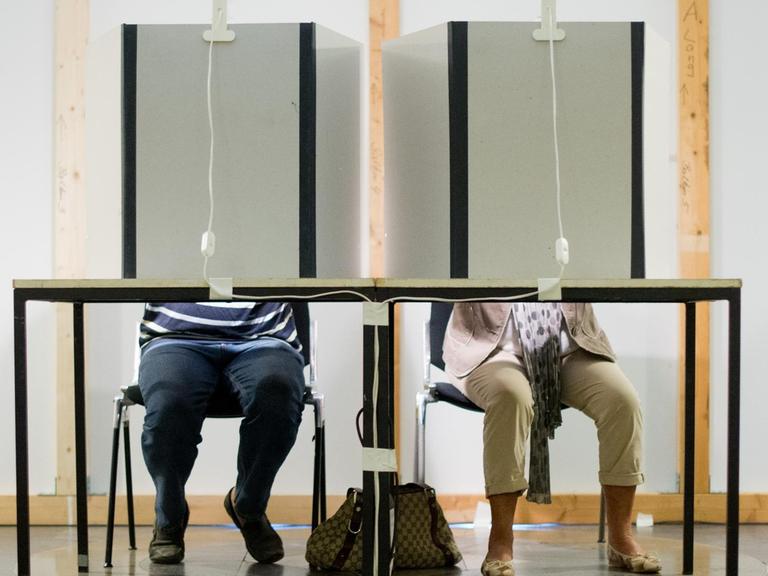 Ein Mann und eine Frau sitzen am 27.08.2013 in einem Wahlraum im Neuen Rathaus in Hannover (Niedersachsen) und füllen ihre Stimmzettel für die Bundestagswahl 2013 aus.