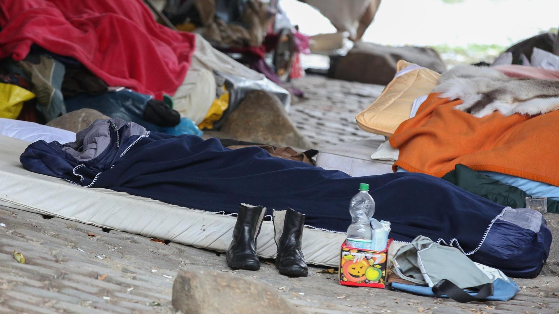 Ein Obdachloser hat sich im Freien in einen Schlafsack verkrochen. Ein Obdachloser hat sich im Freien in einen Schlafsack verkrochen.