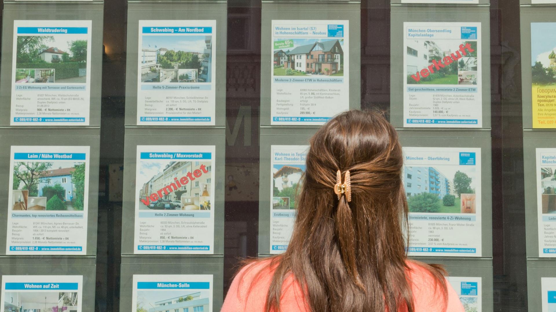 Ein Frau steht in München vor dem Büro eines Immobilienmaklers Ein Frau steht in München vor dem Büro eines Immobilienmaklers