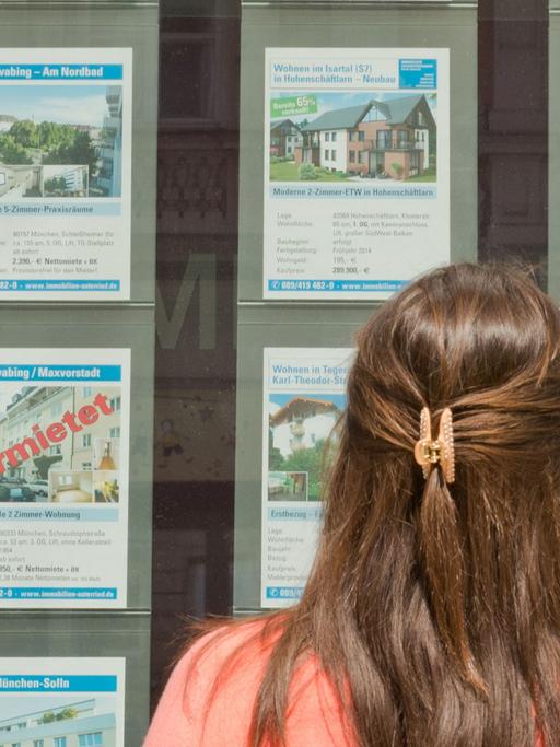 Ein Frau steht in München vor dem Büro eines Immobilienmaklers