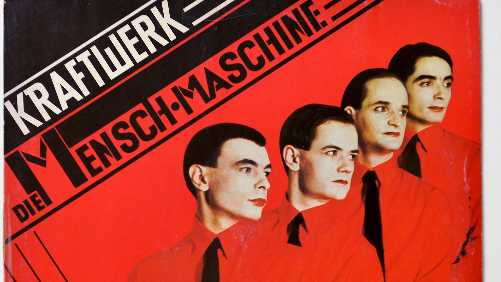Die Musiker der Gruppe Kraftwerk stehen in roten hemden vor einem roten Hintergrund versetzt hintereinander und schauen nach rechts.