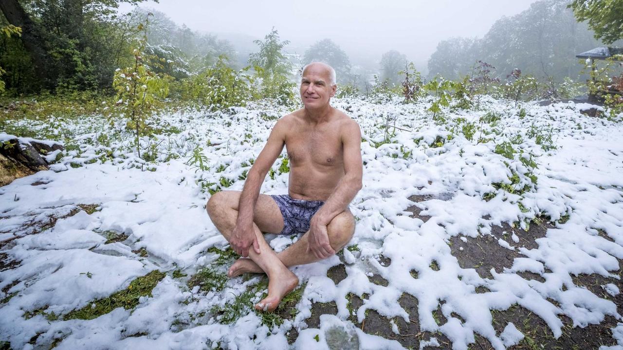 Ein älterer Mann sitzt nur in Unterhose auf einer schneebedeckten Wiese. Ein älterer Mann sitzt nur in Unterhose auf einer schneebedeckten Wiese.