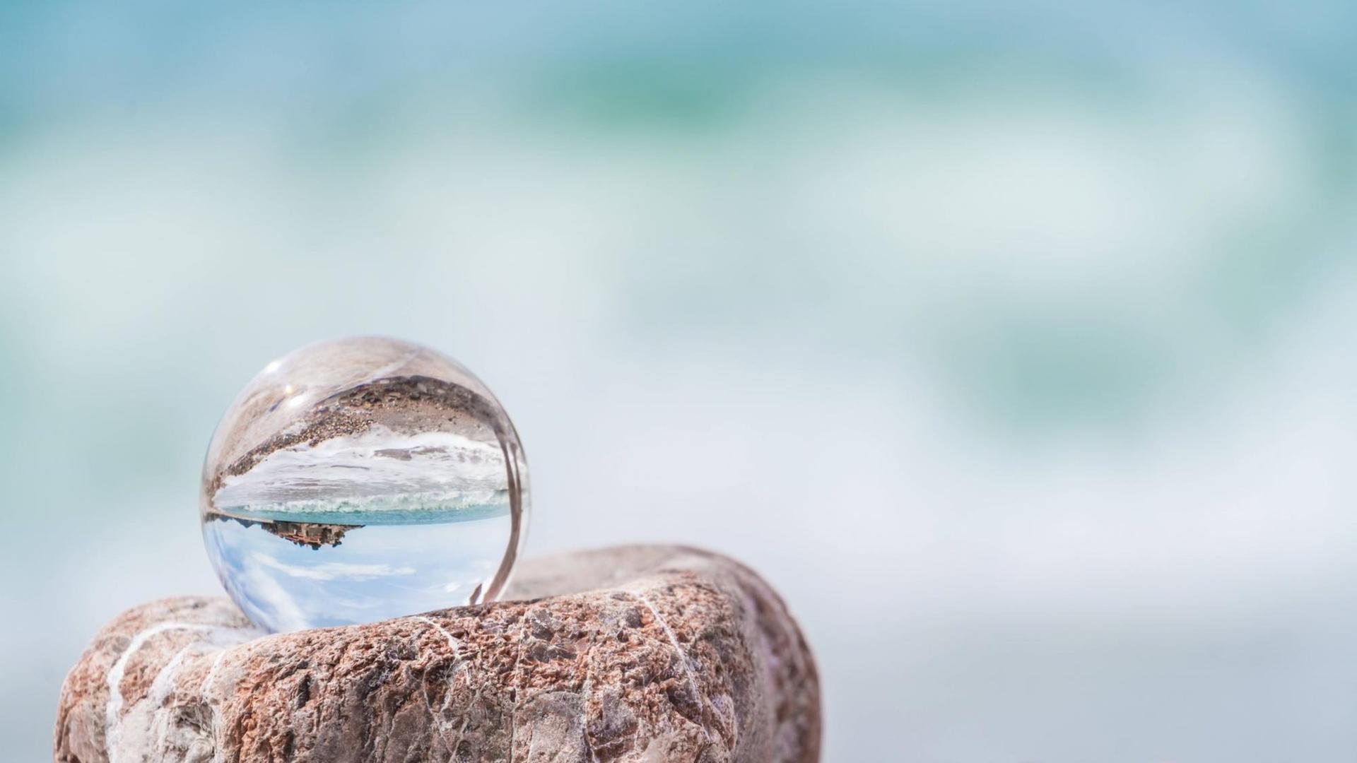 In einer Glaskugel spiegelt sich die Adriaküste, die im Hintergrund nur unscharf zu sehen ist. In einer Glaskugel spiegelt sich die Adriaküste, die im Hintergrund nur unscharf zu sehen ist.