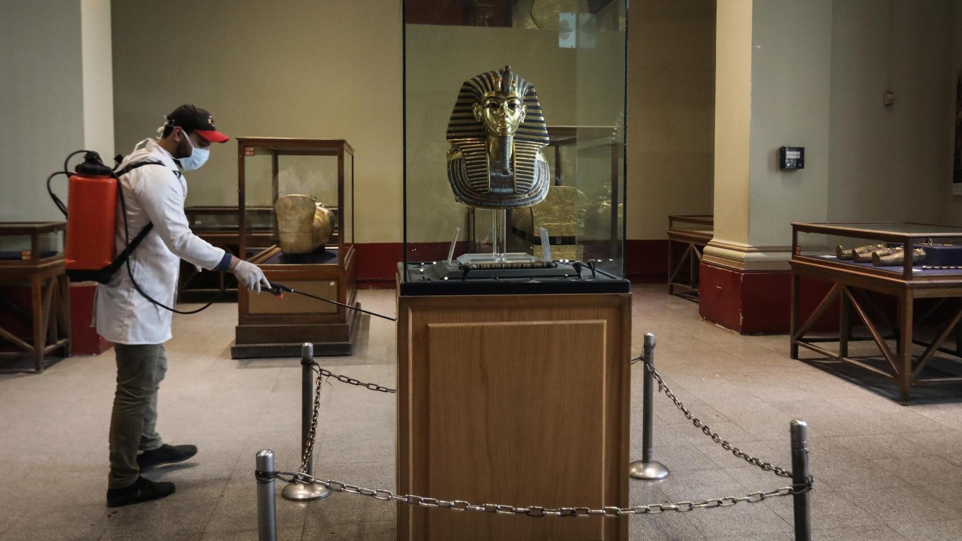 Ein Arbeiter in Schutzanzug sprüht Desinfektionsmittel um die im Ägyptischen Museum ausgestellte goldene Maske des Königs Tutanchamun.