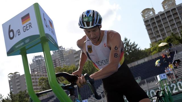 Der deutsche Triathlet Jonas Schomburg nimmt bei den Olympischen Spielen in Tokio in der Wechselzone sein Rennrad in Empfang.