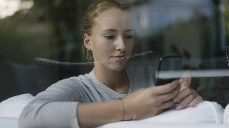 Ein weiblicher Teenager schaut auf das Smartphone Ein weiblicher Teenager schaut auf das Smartphone