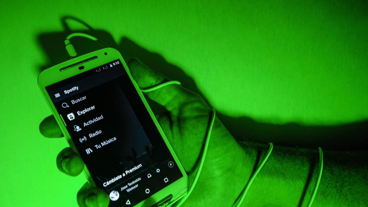 Das Bild zeigt eine Hand, die ein Smartphone hält und Schnur-Kopfkörer sind um das Handgelenk gewickelt. Das Bild zeigt eine Hand, die ein Smartphone hält und Schnur-Kopfkörer sind um das Handgelenk gewickelt.