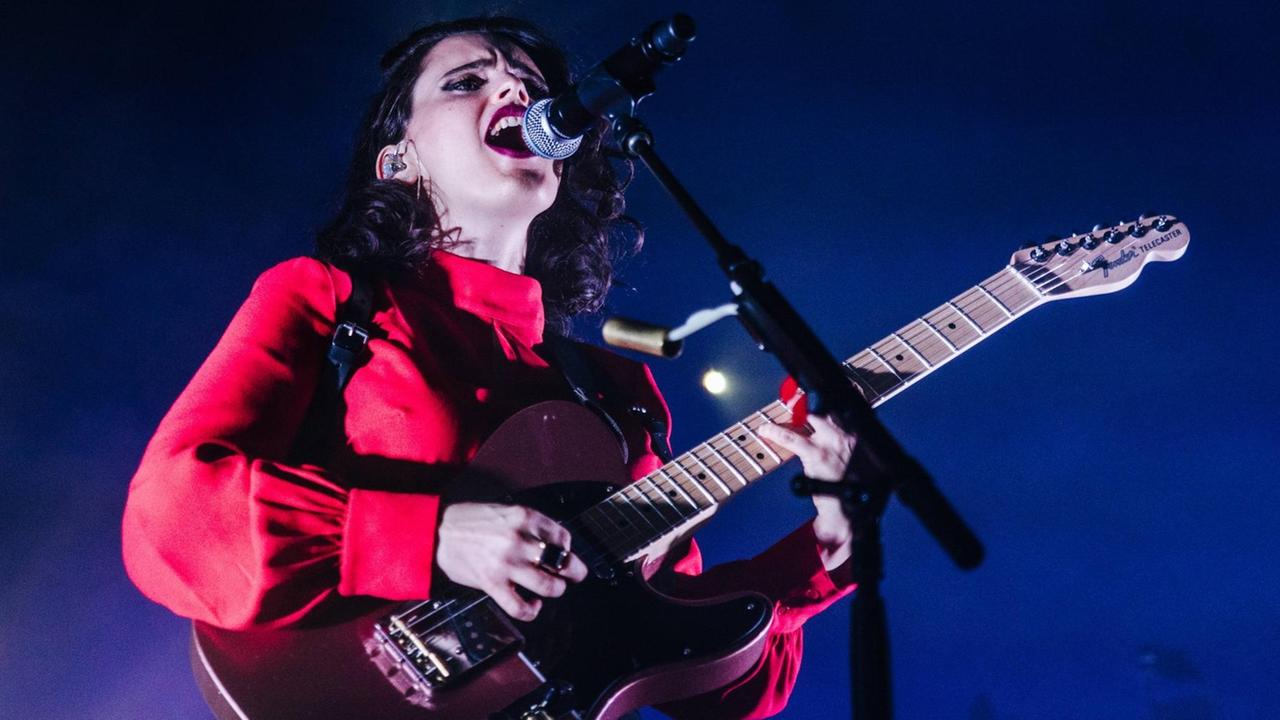 Eine Frau mit Gitarre steht auf einer Bühne. Eine Frau mit Gitarre steht auf einer Bühne.