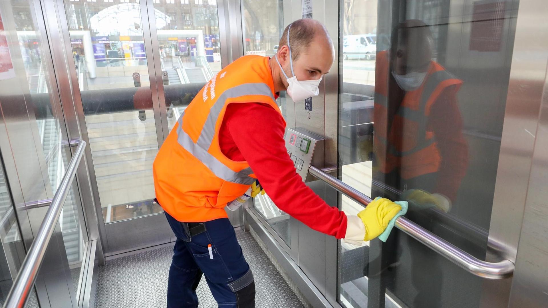 Ein Mitarbeiter der Deutschen Bahn desinfiziert nach einer Reinigung einen Fahrstuhl