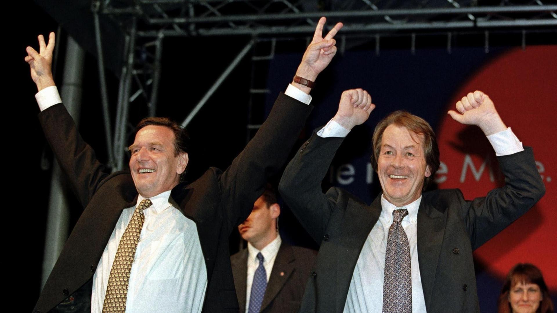Gerhard Schröder (li.) und Franz Müntefering jubeln nach gewonnener Bundestagswahl auf der Bühne vor der SPD-Parteizentrale 1998 in Bonn. Gerhard Schröder (li.) und Franz Müntefering jubeln nach gewonnener Bundestagswahl auf der Bühne vor der SPD-Parteizentrale 1998 in Bonn.