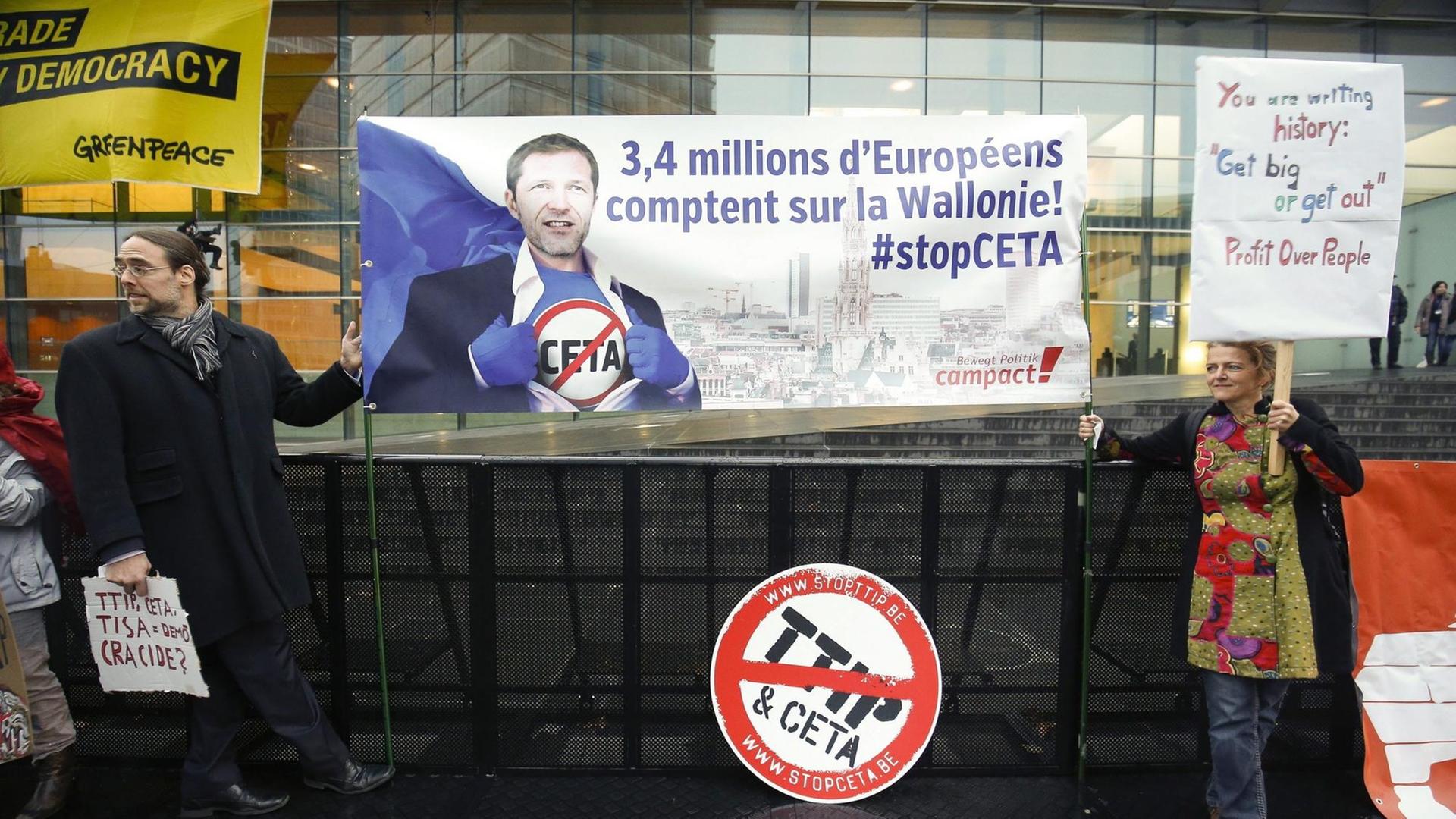 Aktivisten mit einem Banner mit der Aufschrift "3,4 Millions d'Européens comptent sur la Wallonie! #stopCETA" und einem Bild des Ministerpräsidenten Pau Magnette Aktivisten mit einem Banner mit der Aufschrift "3,4 Millions d'Européens comptent sur la Wallonie! #stopCETA" und einem Bild des Ministerpräsidenten Pau Magnette