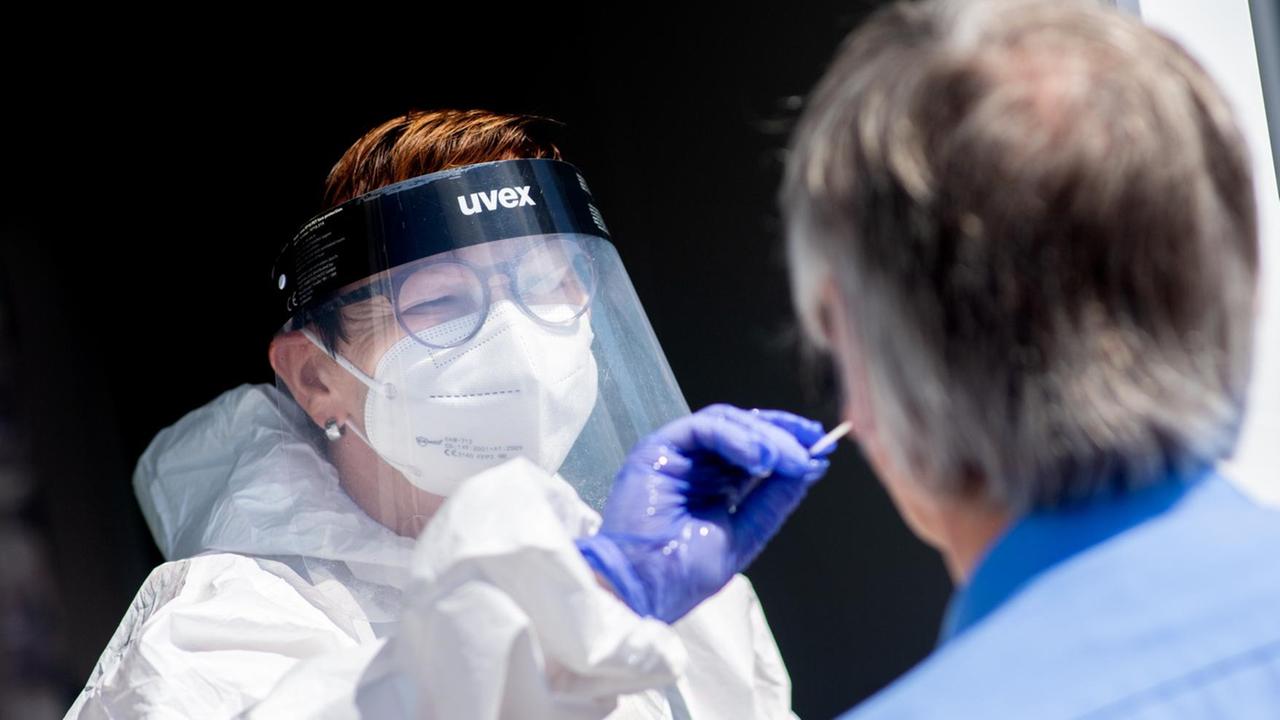 Eine Mitarbeiterin eines Testcenters am Fähranleger nimmt einen Abstrich von einem Touristen. Eine Mitarbeiterin eines Testcenters am Fähranleger nimmt einen Abstrich von einem Touristen.