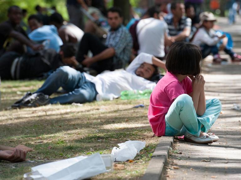 Ein Flüchtlingskind sitzt in Berlin auf dem Gelände des Landesamtes für Gesundheit und Soziales (LaGeSo) auf einem Bordstein.