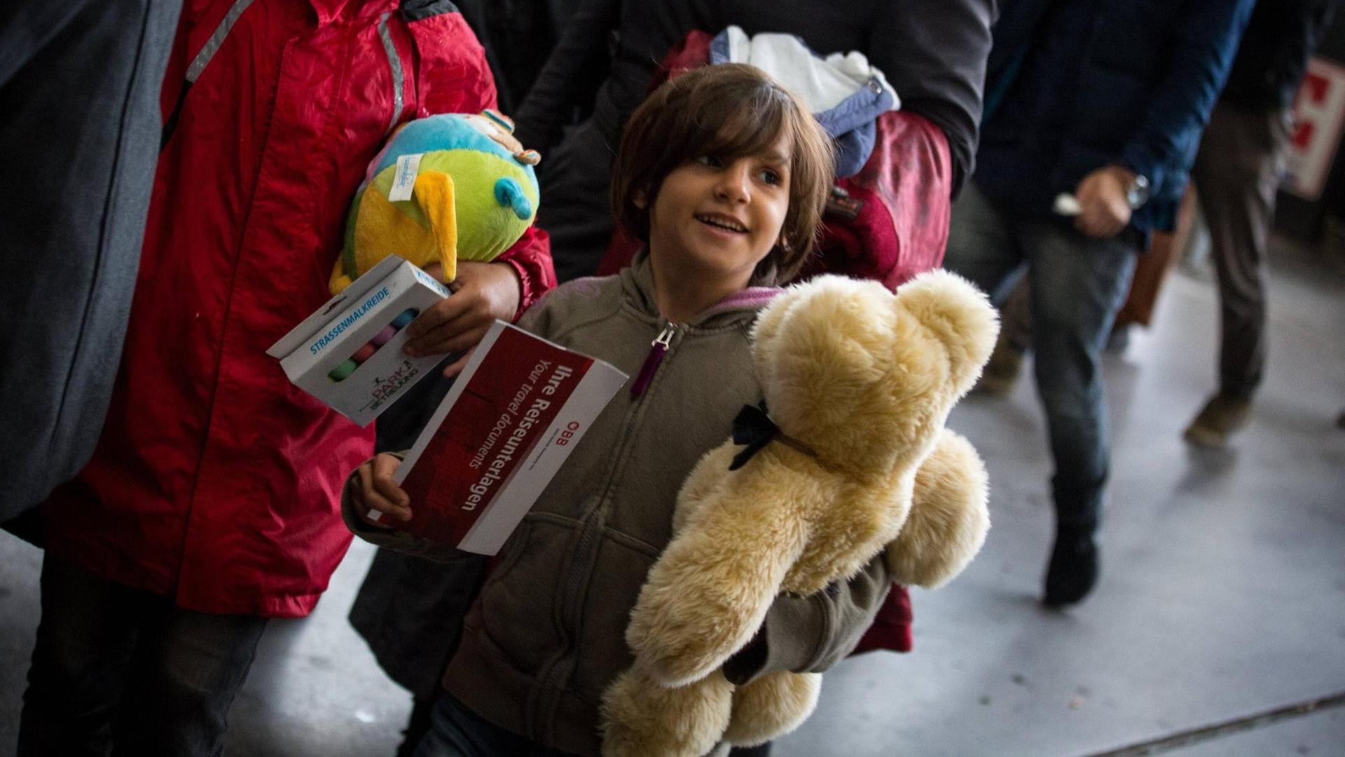 Flüchtlingskind mit einem Teddybär im Arm auf dem Bahnhof. Flüchtlingskind mit einem Teddybär im Arm auf dem Bahnhof.