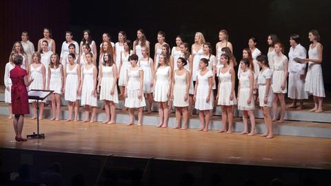Der Chor steht mit weißen Kleidern und barfuß auf der Bühne.
