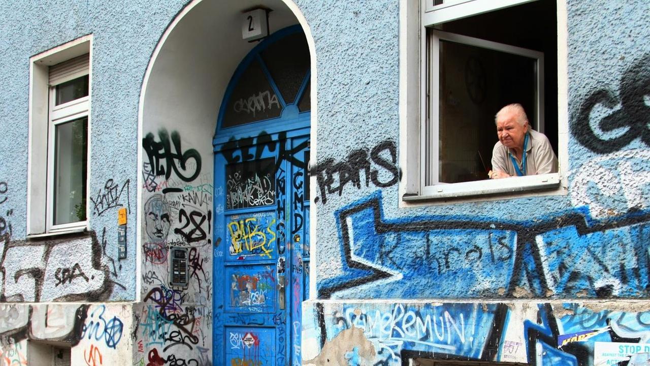 Eine alte Frau blickt aus dem Fenster ihrer Wohnung in Berlin Eine alte Frau blickt aus dem Fenster ihrer Wohnung in Berlin
