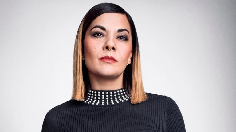 Reyhan Şahin, in schwarzem Rollkragenpullover und schwarzem Lederrock, schaut lässig und herausfordernd in die Kamera. Reyhan Şahin, in schwarzem Rollkragenpullover und schwarzem Lederrock, schaut lässig und herausfordernd in die Kamera.