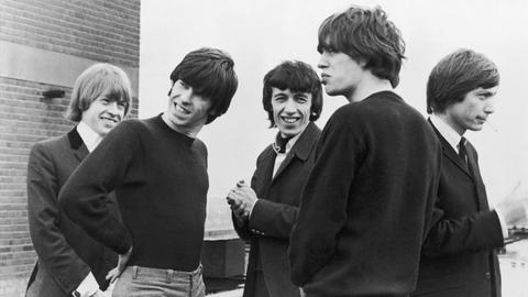 S/w-Bild: Fünf junge Männer mit längeren Haaren stehen in Pullover oder Jackett beieinander.