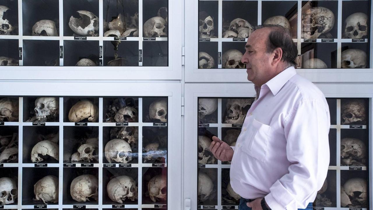 Ein Mitarbeiter des Kulturverbands von Distomo vor Schädeln von Dorfbewohnern, die von Nationalsozialisten im Zweiten Weltkrieg massakriert wurden.
Ein Mitarbeiter des Kulturverbands von Distomo vor Schädeln von Dorfbewohnern, die von Nationalsozialisten im Zweiten Weltkrieg massakriert wurden.