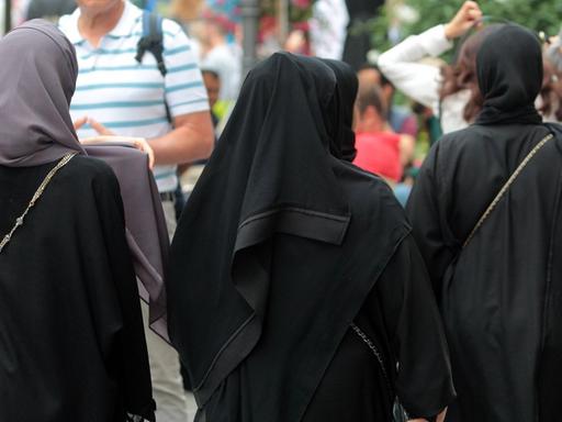 Arabische Muslima mit Burkas spazieren in der Innenstadt von München.