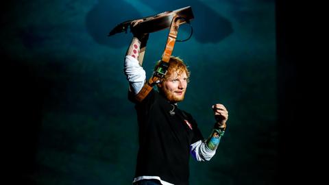 Der Singer und Songwriter Ed Sheeran steht beim Sziget Festival in Budapest auf der Bühne und reckt eine Gitarre in die Höhe.