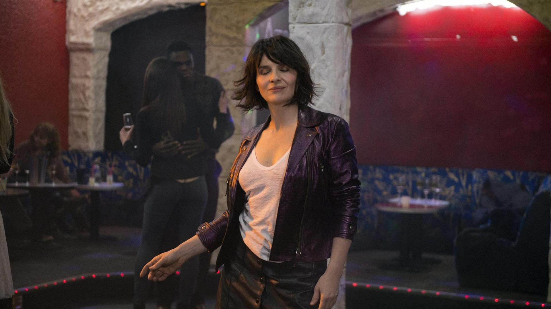 Juliette Binoche tanzt mit geschlossenen Augen allein auf einer Tanzfläche