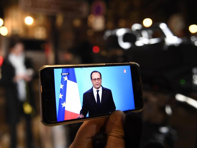 Die Rede von Frankreichs Präsident Hollande ist auf einem Handydisplay zu sehen.