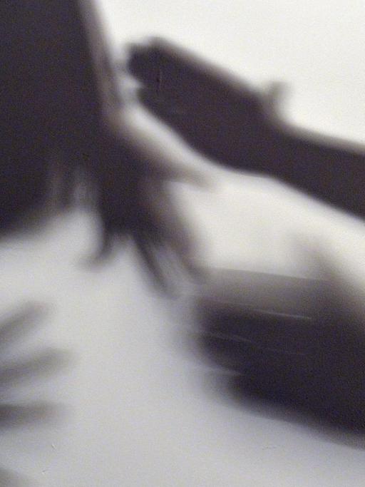 Gestelltes Bild zum Thema häusliche Gewalt - Schatten zeigen, wie eine Frau versucht, sich am vor der Gewalt eines Mannes zu schützen.