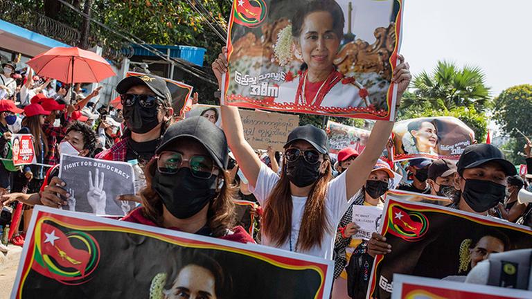 Menschen halten Plakate von Aung San Suu Kyi