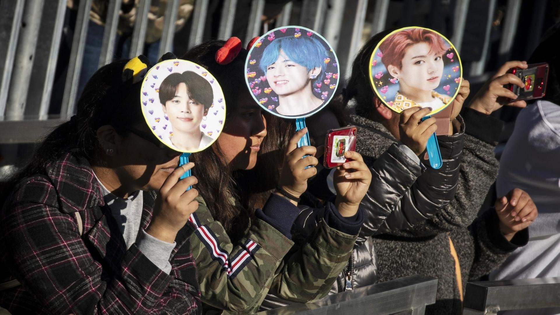 Fans warten auf den Auftritt der K-Pop Gruppe BTS im Central Park, New York und schützen sich mit Fächern, auf den die einzelnen Bandmitglieder abgebildet sind, vor de Sonne. Fans warten auf den Auftritt der K-Pop Gruppe BTS im Central Park, New York und schützen sich mit Fächern, auf den die einzelnen Bandmitglieder abgebildet sind, vor de Sonne.