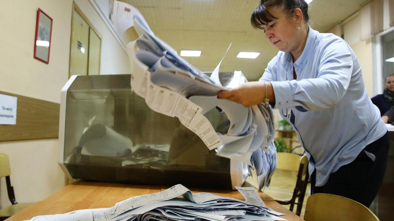 Eine Wahl-Helferin legt einen großen Stimm-Zettel auf einen Stapel. Eine Wahl-Helferin legt einen großen Stimm-Zettel auf einen Stapel.