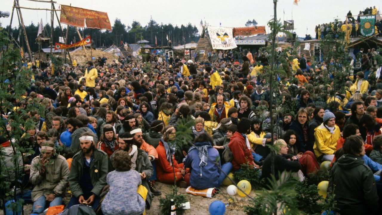 Protestanten sitzen auf dem Boden vor dem Hüttendorf der "Republik Freies Wendland". 