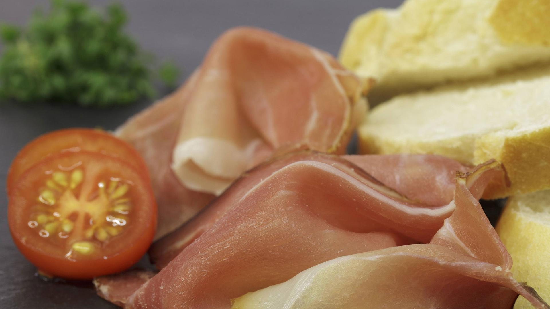 Schinken, Brot und Tomate angerichtet auf einem Brett. Schinken, Brot und Tomate angerichtet auf einem Brett.
