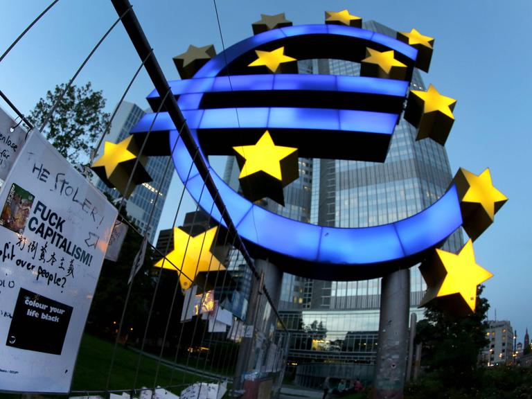 Das Eurozeichen vor der Europäischen Zentralbank (EZB) in Frankfurt/Main mit Protestplakat