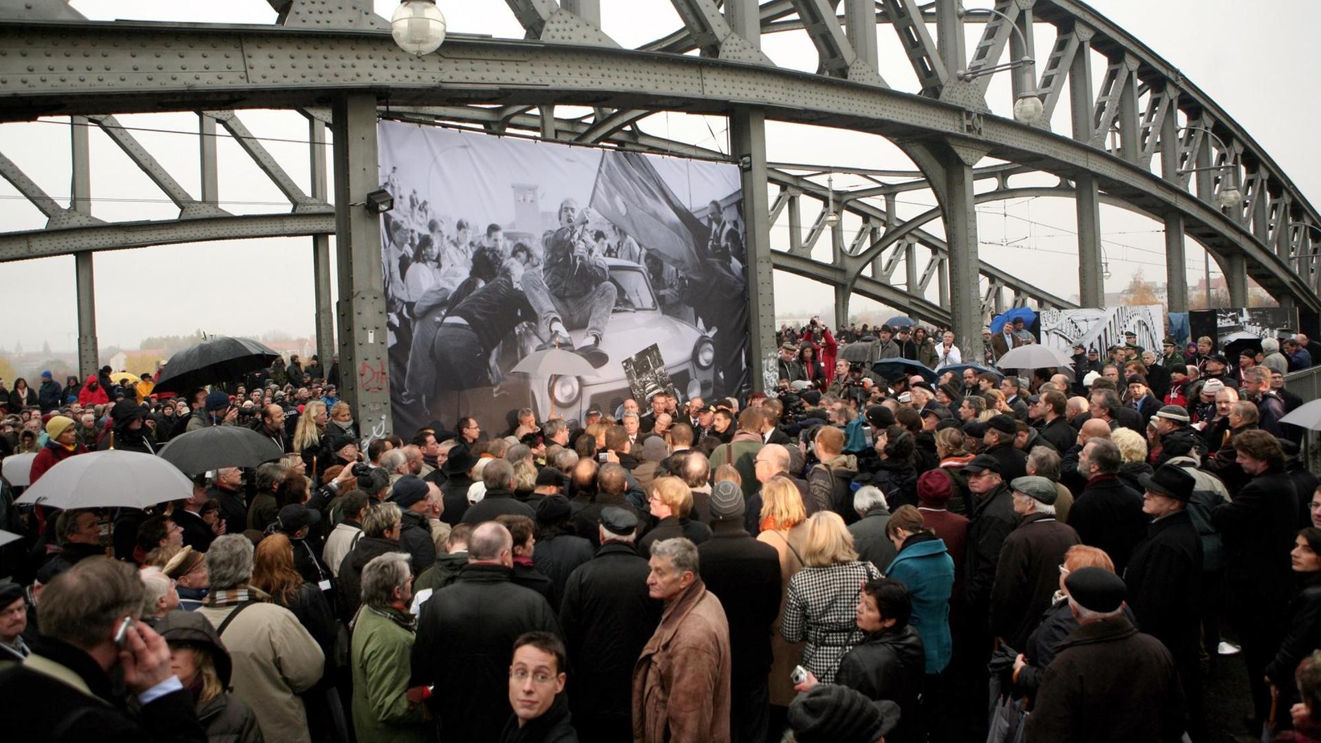 Das Bild zeigt wie an der Brücke an der Bornholmer Straße große Menschenmassen versuchen, einen Blick auf Bundeskanzlerin Angela Merkel, den ehemaligen Sowjetpräsidenten Michail Gorbatschow und den ehemaligen polnischen Solidaritätsführer Lech Walesa zum 20. Jahrestag des Mauerfalls am 9. November 2009 in Berlin zu werfen. Die drei Anführer sollten die Brücke und den darunter liegenden Bahnhof besuchen, weil dort 1989 die Wachen den ersten Grenzübergang öffneten und den Ostberlinern erlaubten, ungehindert nach Westberlin zu gehen. Das Bild zeigt wie an der Brücke an der Bornholmer Straße große Menschenmassen versuchen, einen Blick auf Bundeskanzlerin Angela Merkel, den ehemaligen Sowjetpräsidenten Michail Gorbatschow und den ehemaligen polnischen Solidaritätsführer Lech Walesa zum 20. Jahrestag des Mauerfalls am 9. November 2009 in Berlin zu werfen. Die drei Anführer sollten die Brücke und den darunter liegenden Bahnhof besuchen, weil dort 1989 die Wachen den ersten Grenzübergang öffneten und den Ostberlinern erlaubten, ungehindert nach Westberlin zu gehen.
