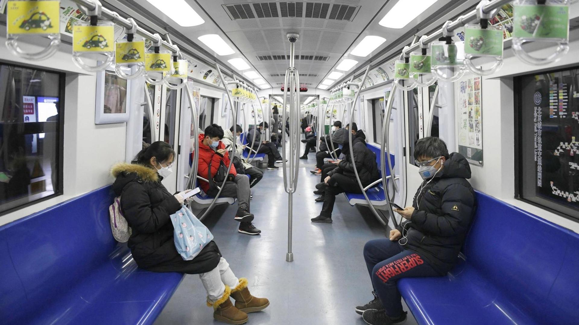 Menschen sitzen mit Schutzmasken in der U-Bahn von Peking/China