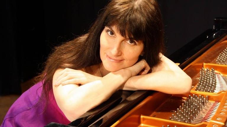 Die Pianistin stützt sich mit ihren Armen auf einem Flügel ab. Die Pianistin stützt sich mit ihren Armen auf einem Flügel ab.