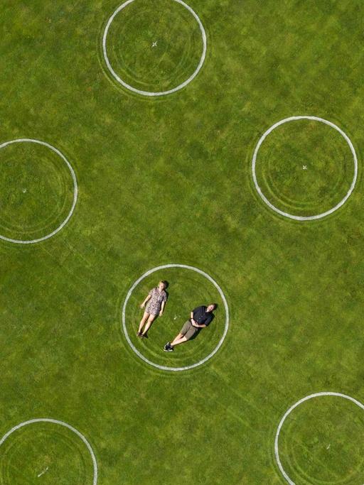 Luftaufnahme eines Stadions mit eingezeichneten Kreidekreisen für die Abstandseinhaltung bei einer Veranstaltung im Jahnstadion, Göttingen. In einem der Kreise liegt ein Paar nebeneinander.