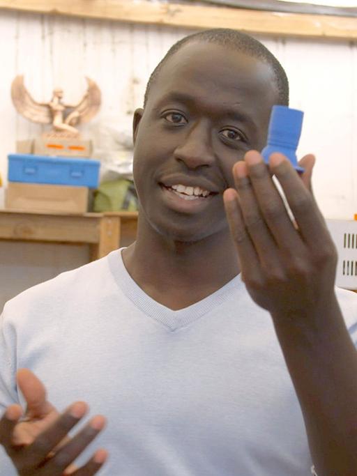 Roy Ombatti von AB3D aus Kenia zeigt ein Ersatzteil, das er mit seinem 3D-Drucker hergestellt hat.