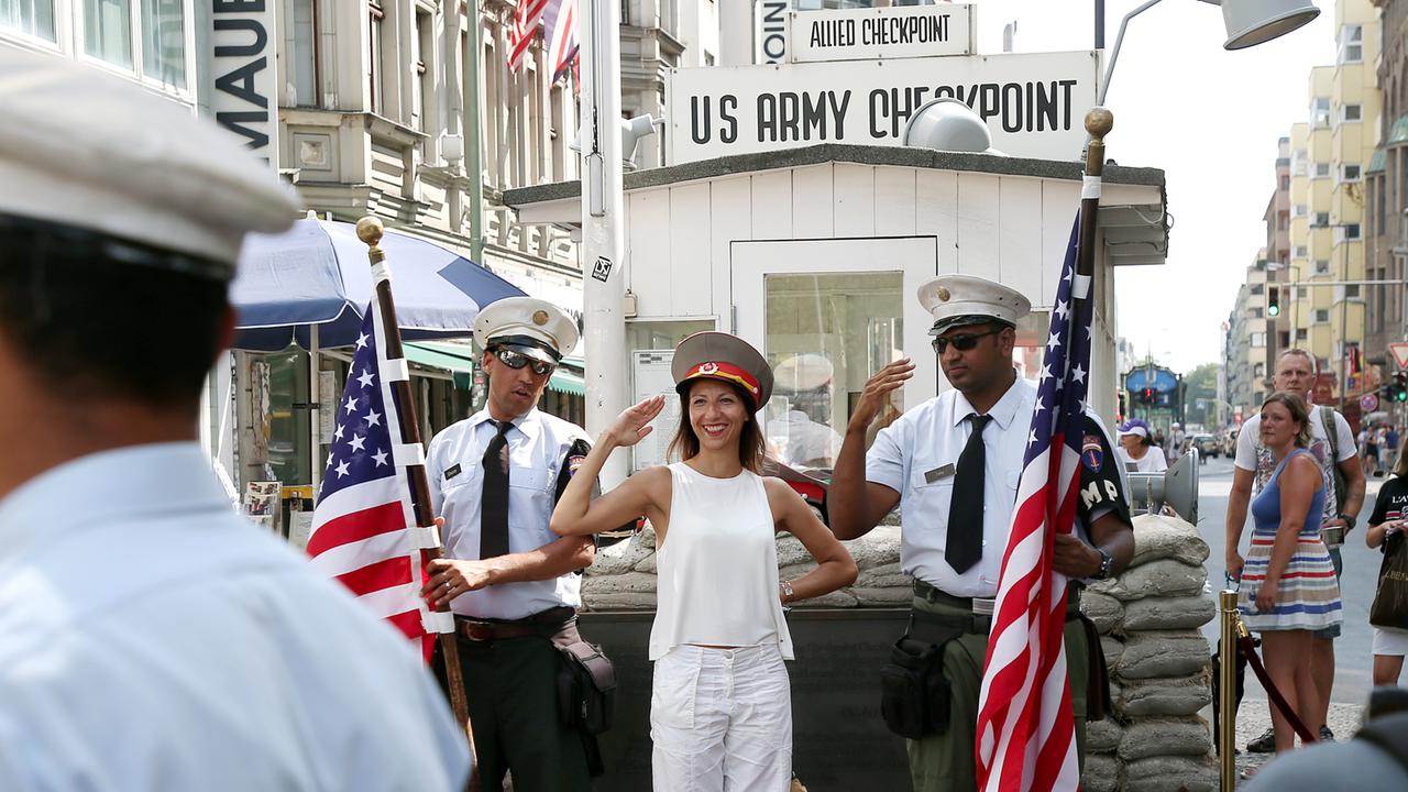 Eine Frau und zwei Soldatendarsteller posieren vor dem ehemaligen Checkpoint Charlie Eine Frau und zwei Soldatendarsteller posieren vor dem ehemaligen Checkpoint Charlie