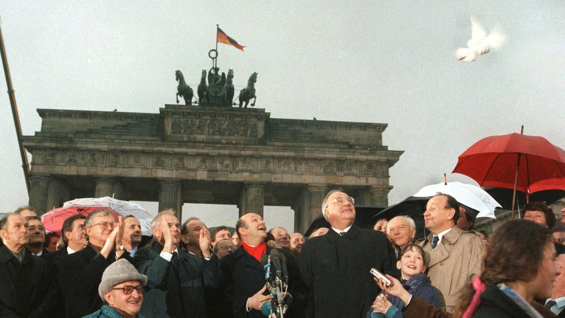 28 Jahre nach dem Mauerbau ist das Brandenburger Tor wieder zugänglich: DDR-Ministerpräsident Hans Modrow und Bundeskanzler Helmut Kohl lassen am 22. Dezember 1989 Friedenstauben aufsteigen. In der Mitte Walter Momper, Regierender Bürgermeister von Berlin. 28 Jahre nach dem Mauerbau ist das Brandenburger Tor wieder zugänglich: DDR-Ministerpräsident Hans Modrow und Bundeskanzler Helmut Kohl lassen am 22. Dezember 1989 Friedenstauben aufsteigen. In der Mitte Walter Momper, Regierender Bürgermeister von Berlin.