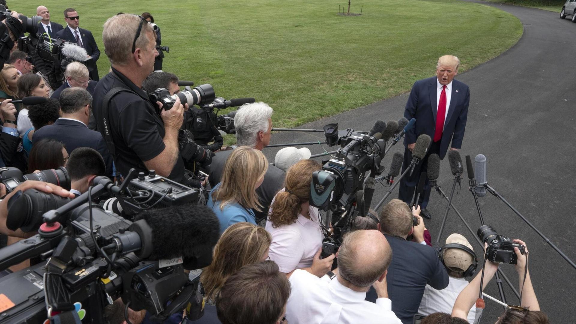 US-Präsident Trump steht vor einer Menschentraube von Journalisten auf einer Straße im Garten des Weißen Hauses. Die Reporter filmen und halten ihm Mikrofone entgegen. US-Präsident Trump steht vor einer Menschentraube von Journalisten auf einer Straße im Garten des Weißen Hauses. Die Reporter filmen und halten ihm Mikrofone entgegen.