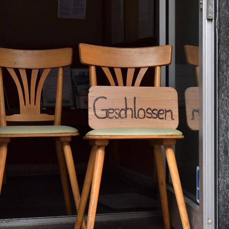 "Geschlossen" steht auf einem Schild, das im auf einem Stuhl im Türrahmen lehnt. 