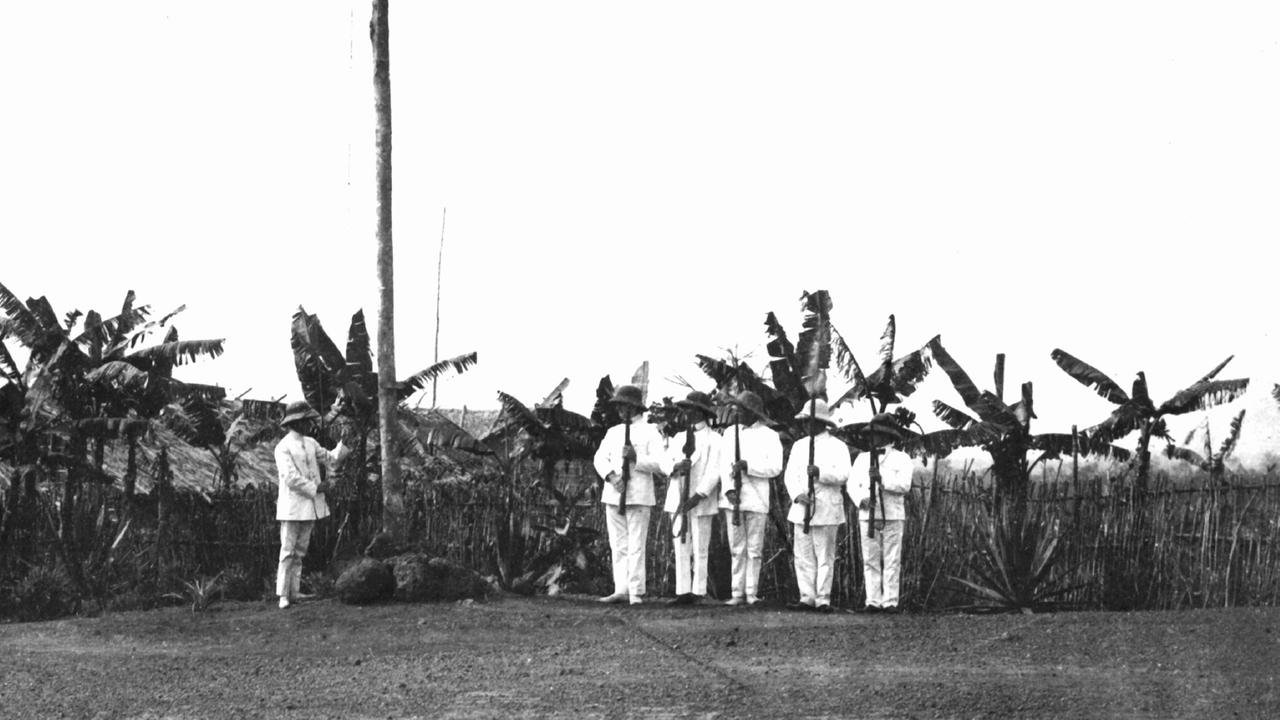 Auf einem Militärstützpunkt in der deutschen Kolonie Kamerun wird von in Tropenanzüge gekleideten Männern eine Fahne gehisst. Eine undatierte Aufnahme aus der Kolonialzeit. Von 1884 bis 1919 war Kamerun eine deutsche Kolonie, dann wurde es unter Großbritannien und Frankreich aufgeteilt.