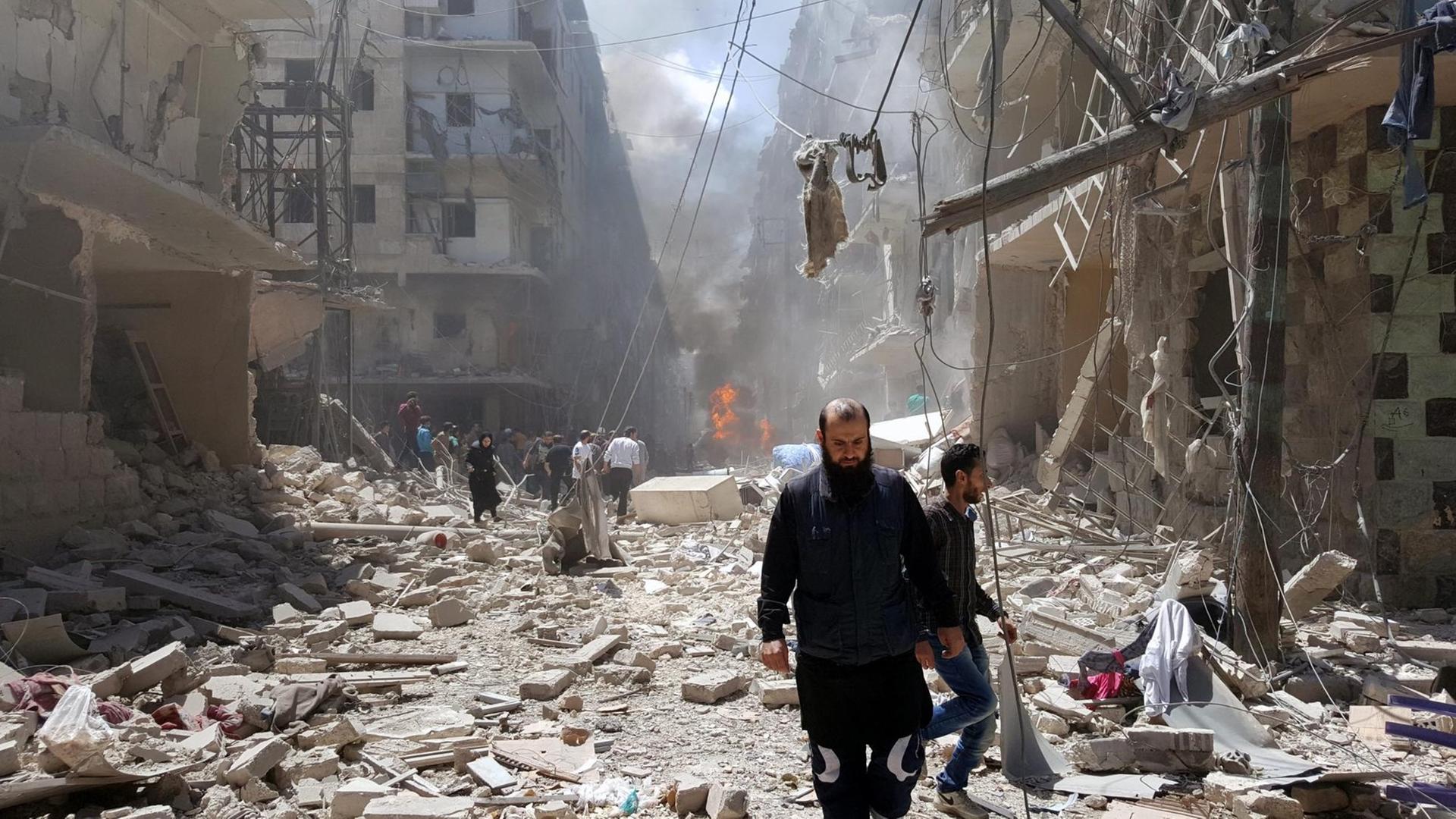 Der von Aufständischen kontrollierte Ostteil Aleppos wird durch Angriffe der syrischen Luftwaffe erschüttert. Sie sehen Syrer, die inmitten von Trümmern laufen. Der von Aufständischen kontrollierte Ostteil Aleppos wird durch Angriffe der syrischen Luftwaffe erschüttert. Sie sehen Syrer, die inmitten von Trümmern laufen.